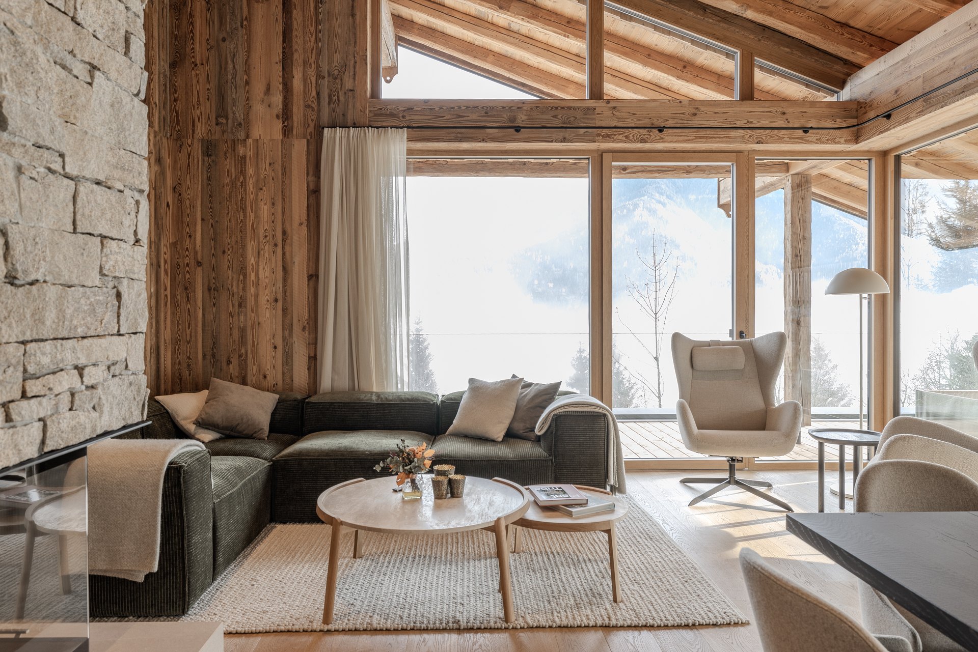 Projekt Schladming: Wohnbereich mit Naturstein, Holz und hellen Vorhängen