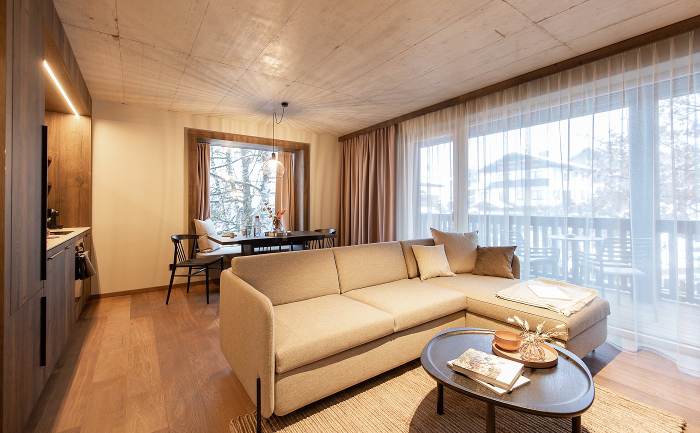 Villa Lisl: Apartment mit beigem Sofa, Holzflächen und großzügigen Vorhängen